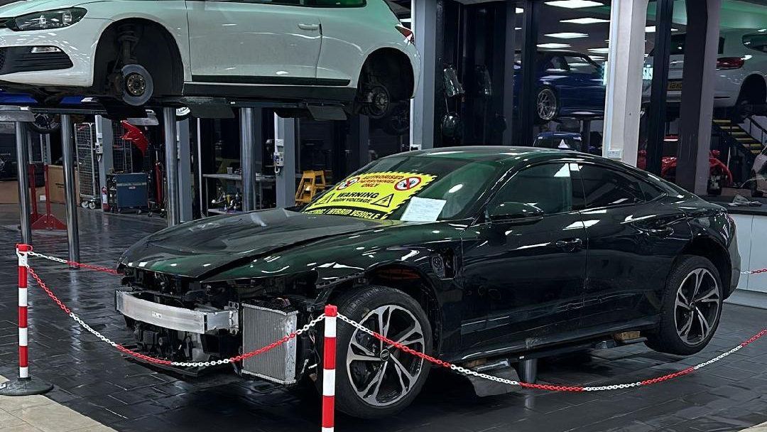 A black car with the front end damaged ready to be repaired