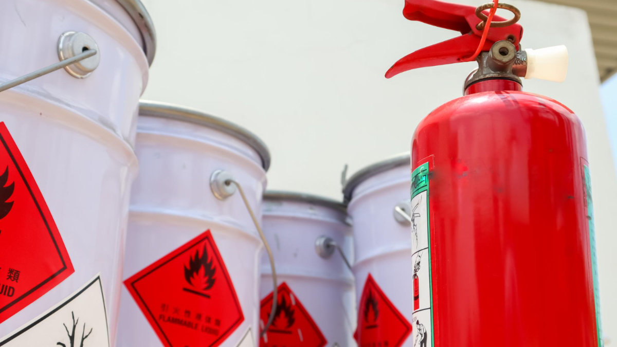 4 barrels of hazardous waste next to a red fire extinguisher